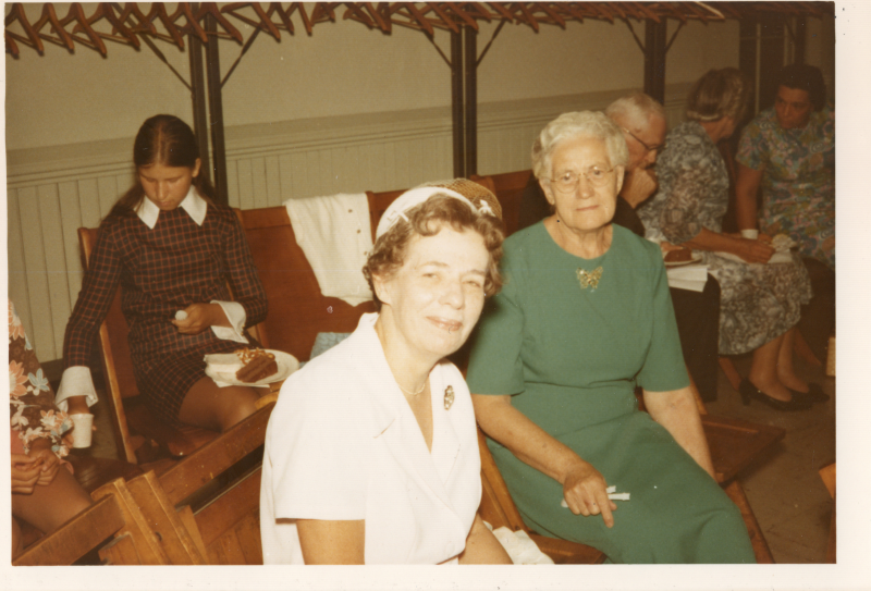 Two seated women smile for a photograph