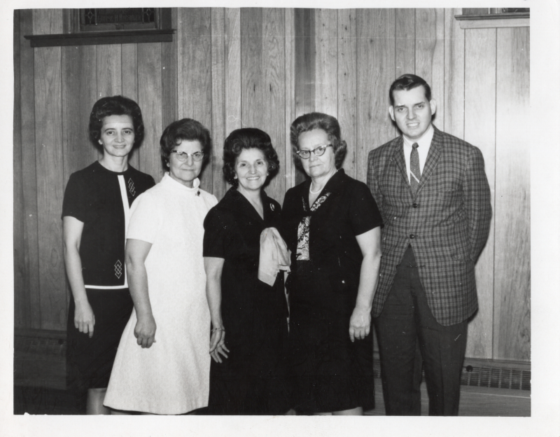 A group of four women and one man pose together