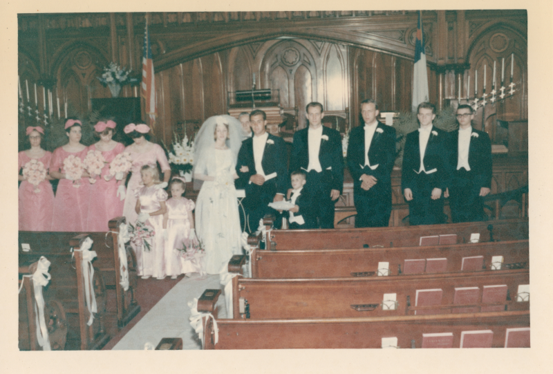 A bride and groom stand with bridesmaids, groomsmen, and flower girls