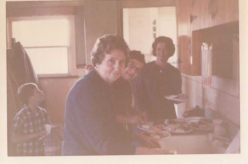 Three women smile while picking up pastries