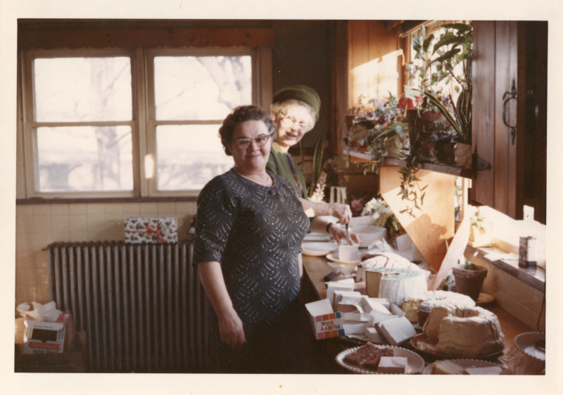 Two women slice cakes
