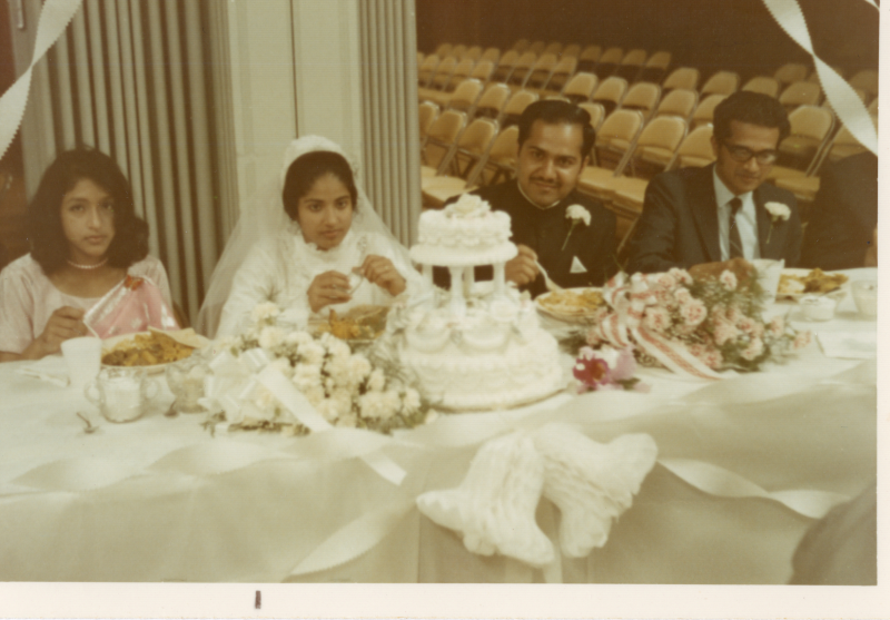 A wedding party sits at a table with a wedding cake
