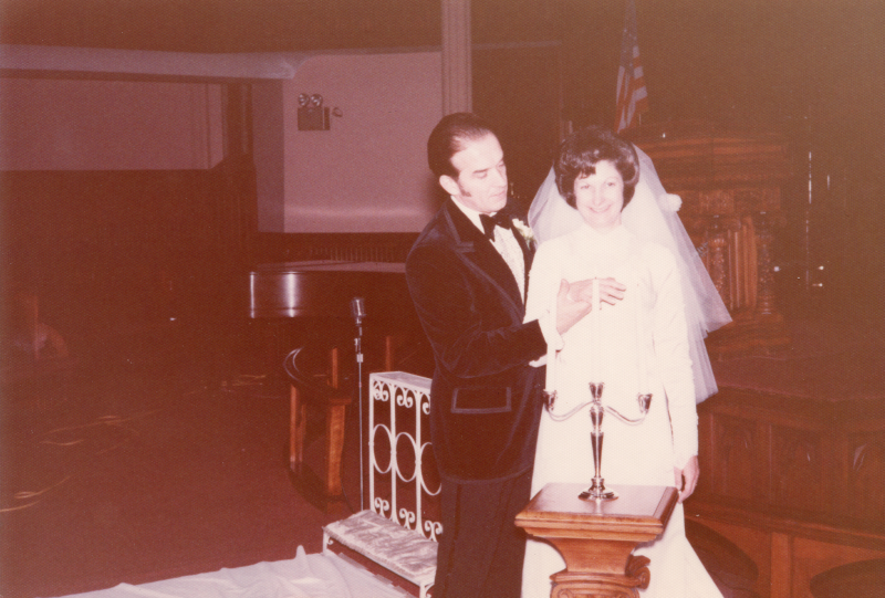 A bride and groom stand in front of candles in the sanctuary at 18th and Spring Garden streets