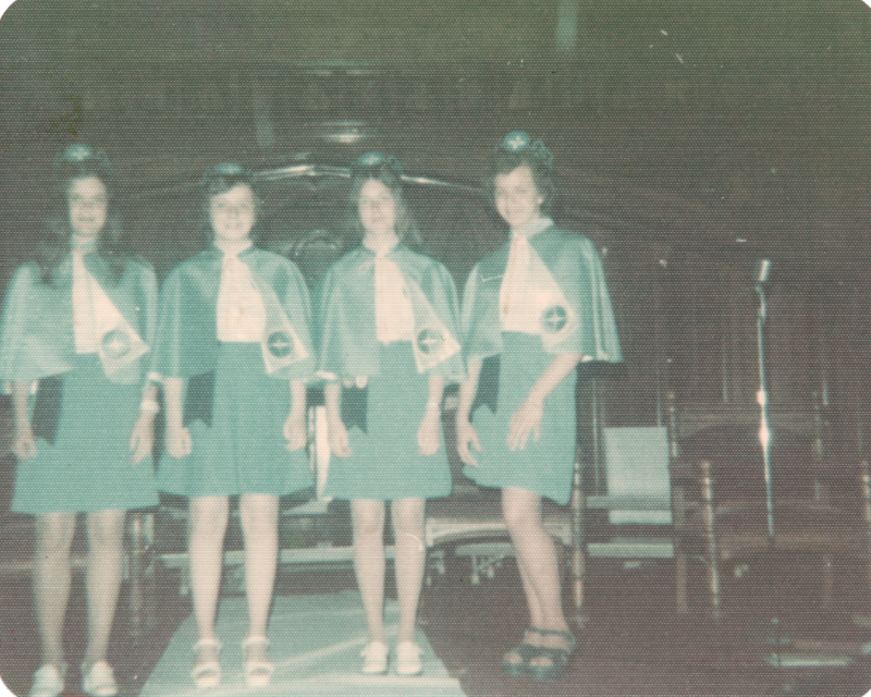 Four missionettes stand on stage