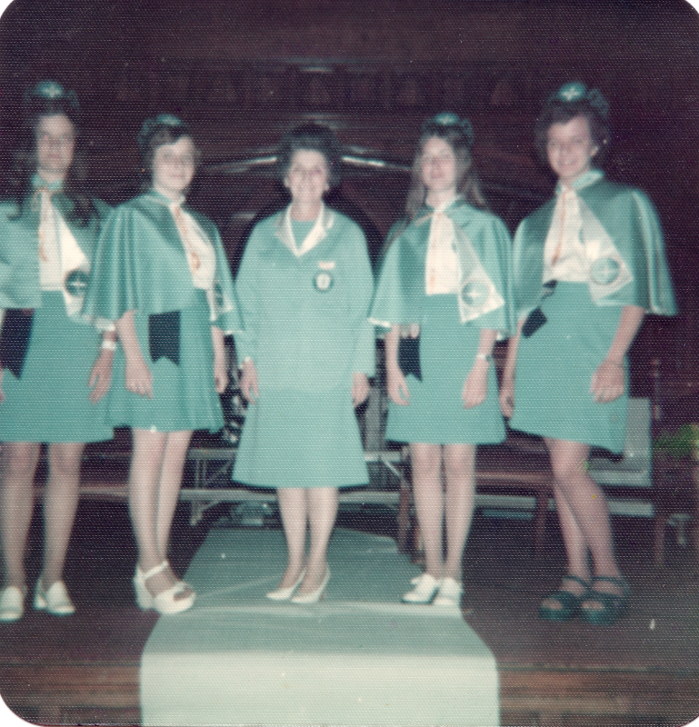 Four missionettes and an adult leader stand on stage