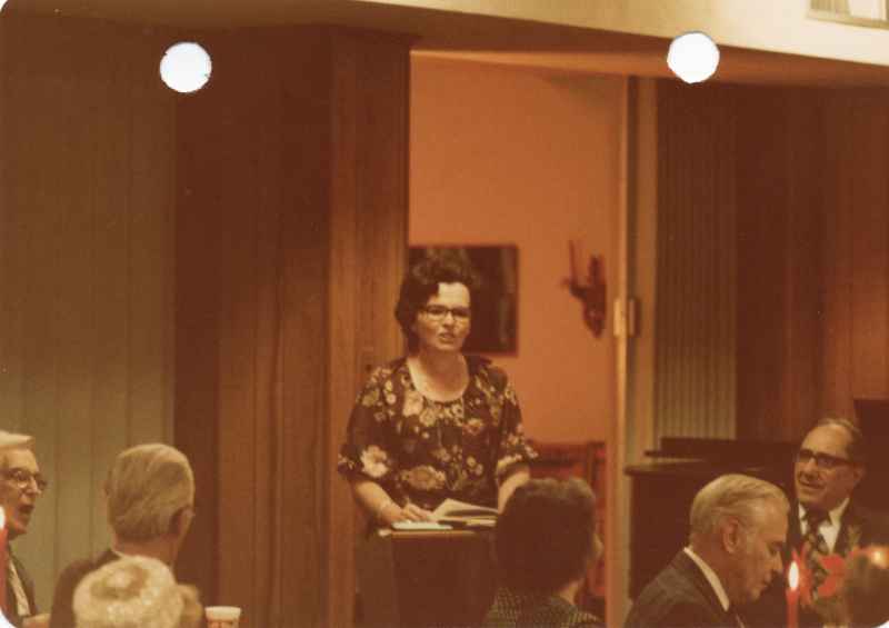 Mrs. Stone stands at a podium and addresses congregants