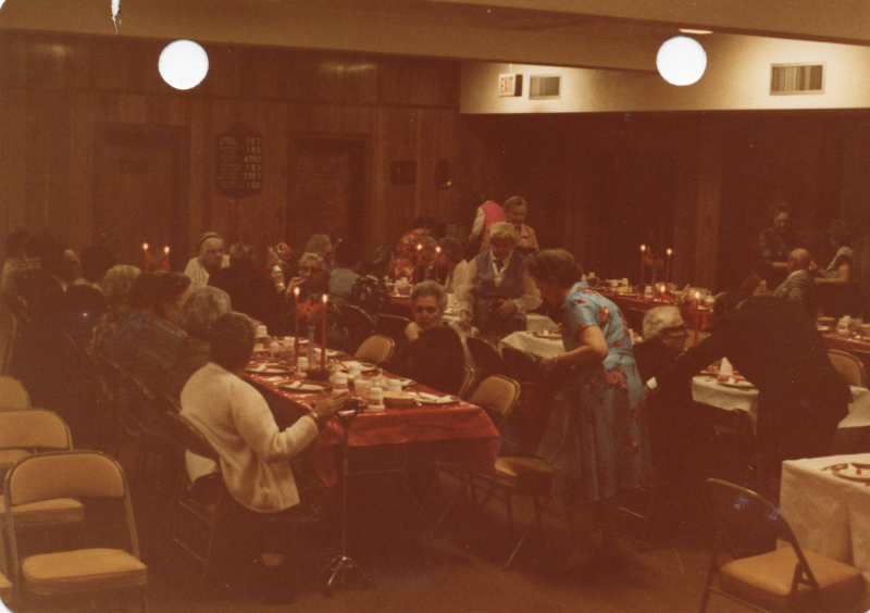 Congregants eat together at long, candle-lit tables
