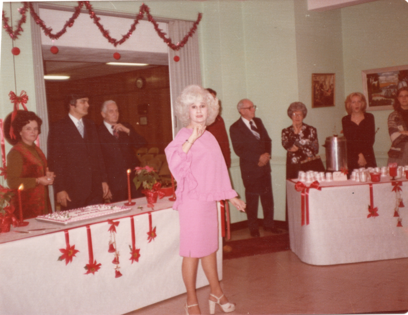 A group of people stand with Christmas decorations and a cake