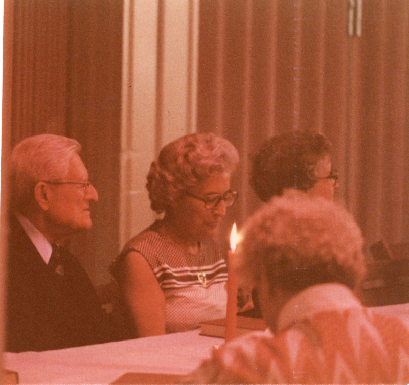 A group sits around a table lit by a candle