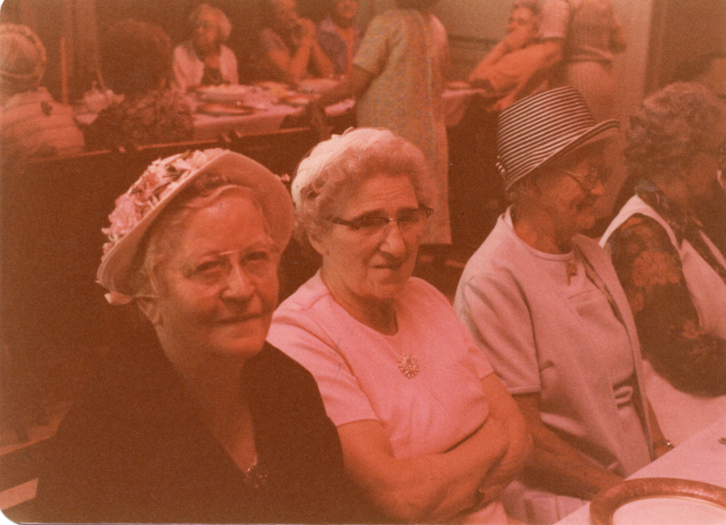 Three older women sit together in a row
