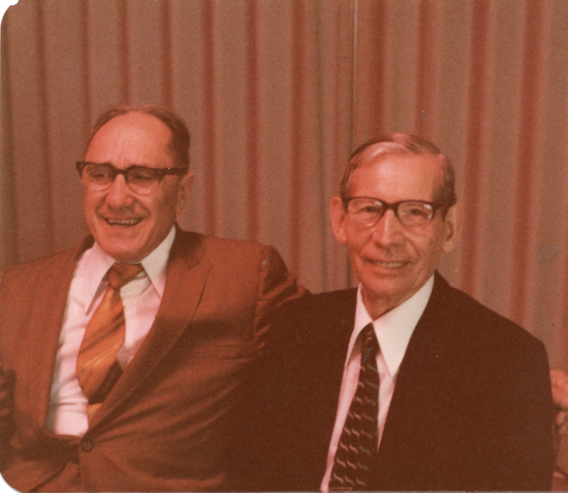 Two smiling men sit next to each other