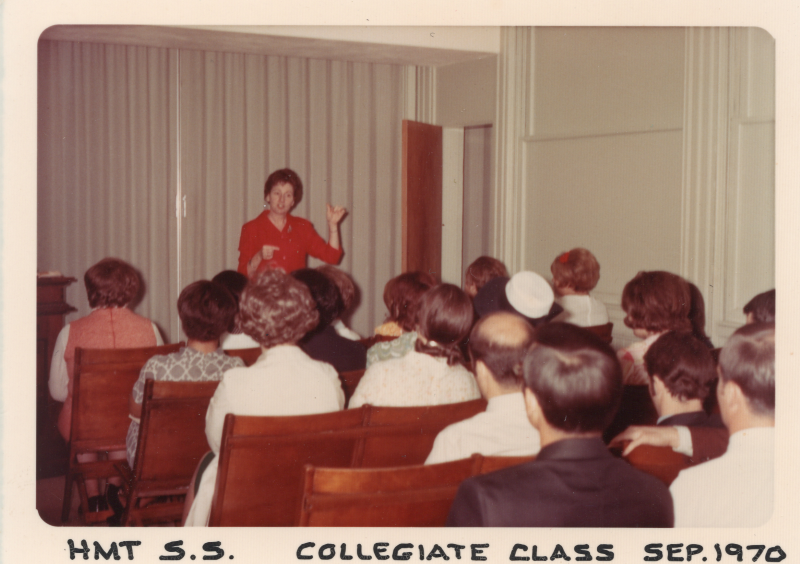 A group faces a woman giving a speech