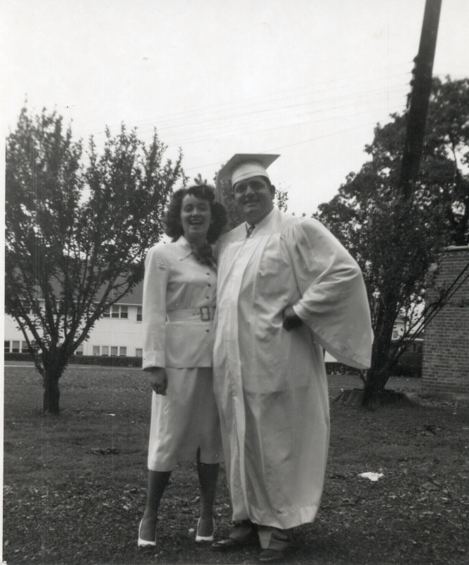 A woman and a boy in a cap and gown pose for a photograph