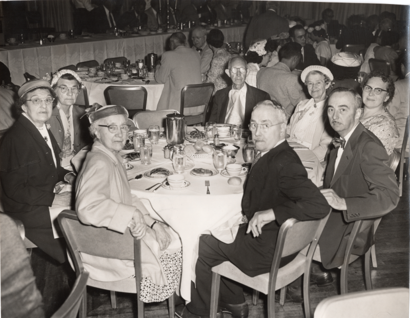 Congregants dining around a circular table smile for a photograph