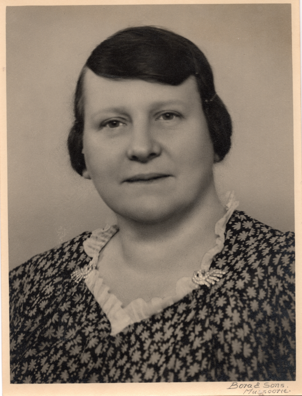 A woman smiles for a portrait with a caption reading, "Bora & Sons. Mussootie."