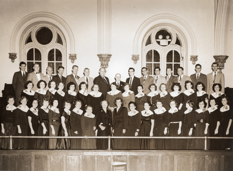 A row of men and two rows of women pose together  for a photograph in the church balcony at 19th and Green streets