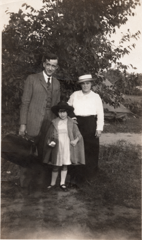 A man, woman, and child pose outside with luggage