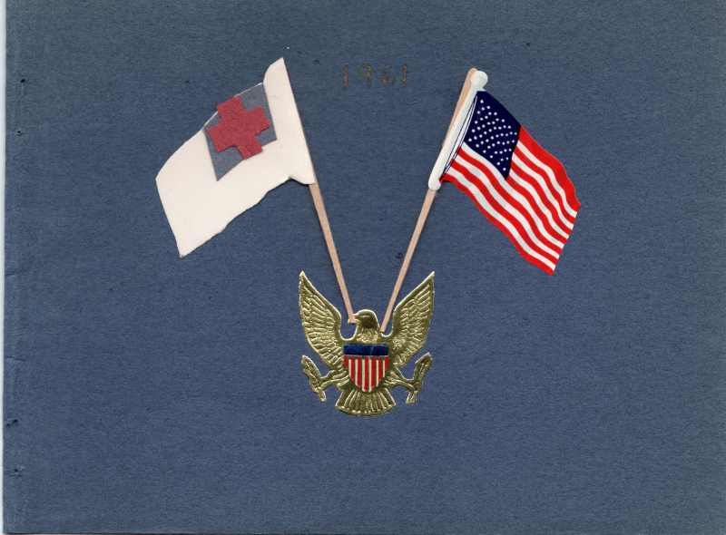 A gold eagle carries the Christian flag and the American flag on blue construction paper with the year 1961 printed in gold ink