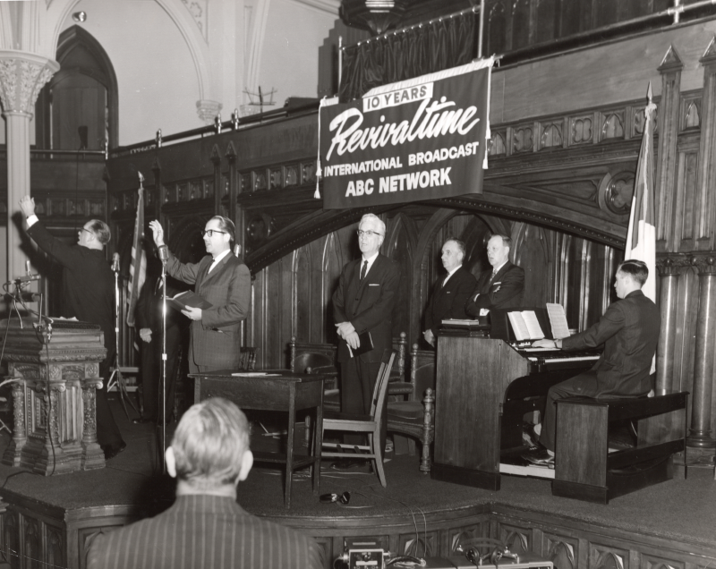 Radio broadcast of Revivaltime withmen singing to an organ in the sanctuary at Highway (18th and Spring Garden) in front of a Revivaltime banner