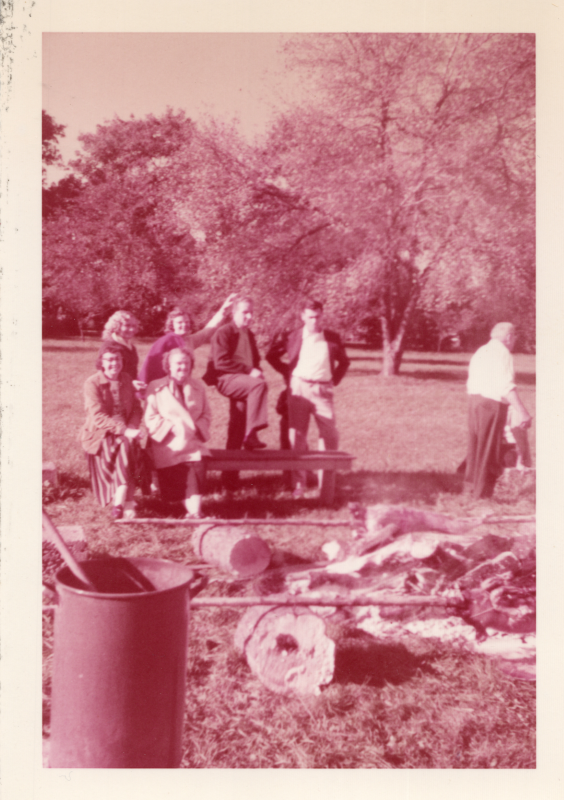 Members of the choir stand around roasting pigs