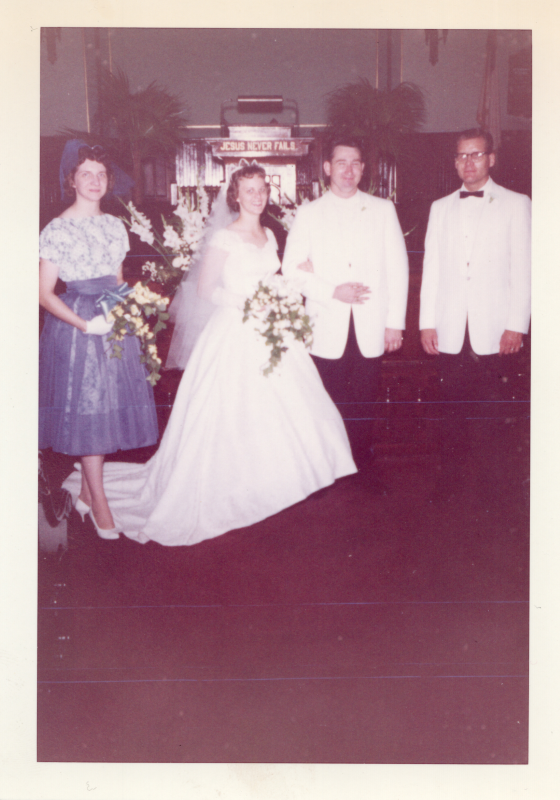 A bride and groom smile with their maid of honor and best man in the sanctuary at 19th and Green streets