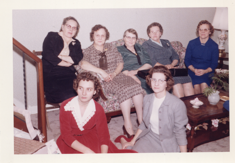 A group of women in a living room smile for a portrait