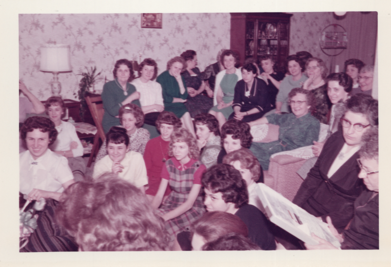 A group of women in a living room turn to look at something
