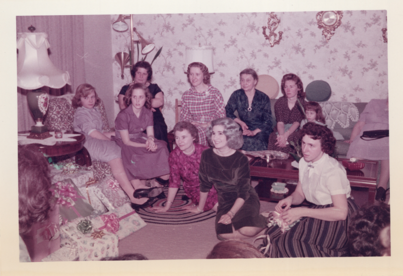 A group of women sat in a circle smile near a pile of wrapped presents