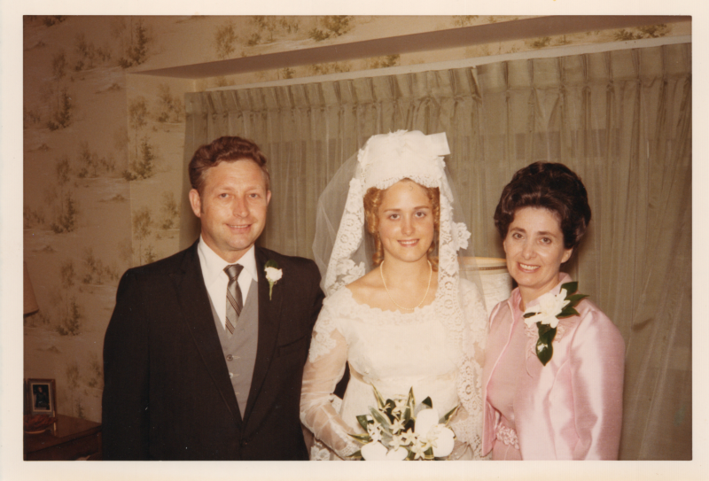A bride poses for a photograph with a man and woman