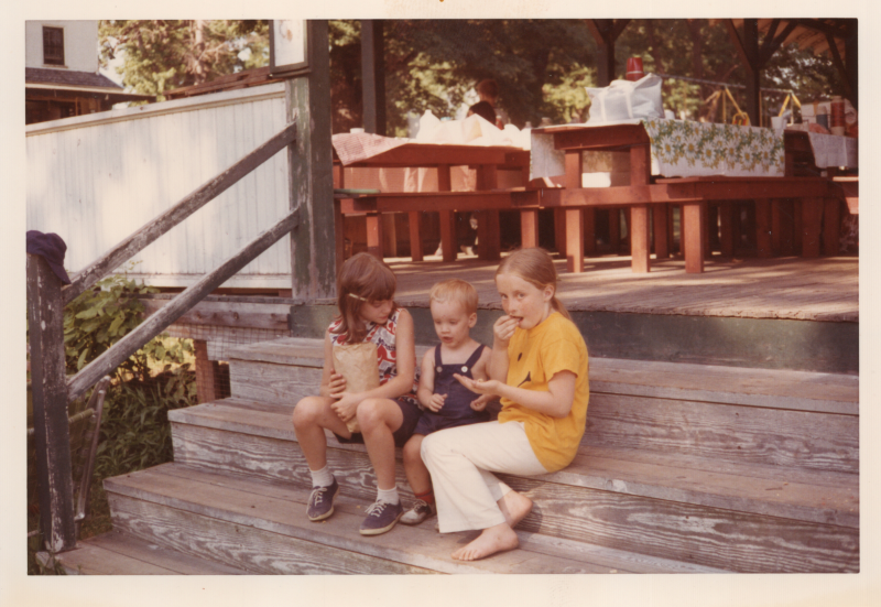 Three children eat outside on steps