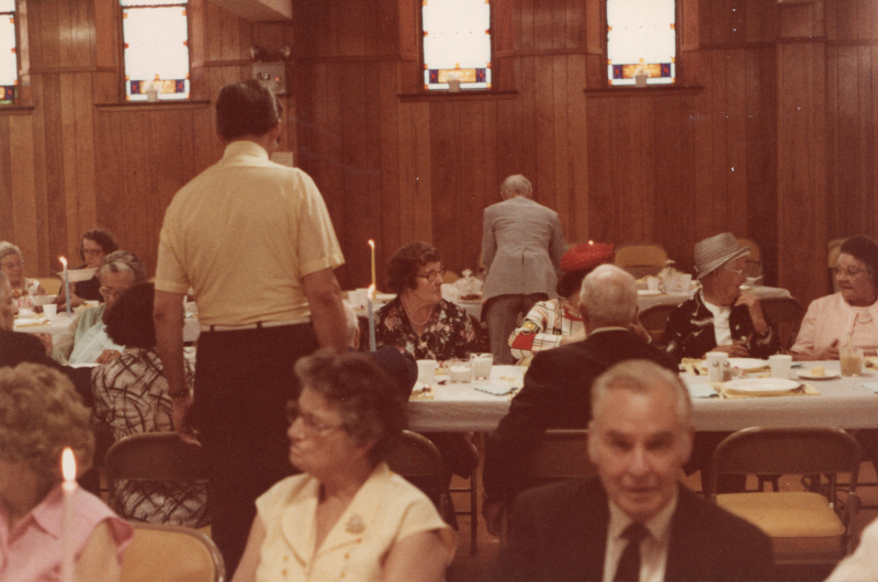 Congregants dine together at long, candlelit tables