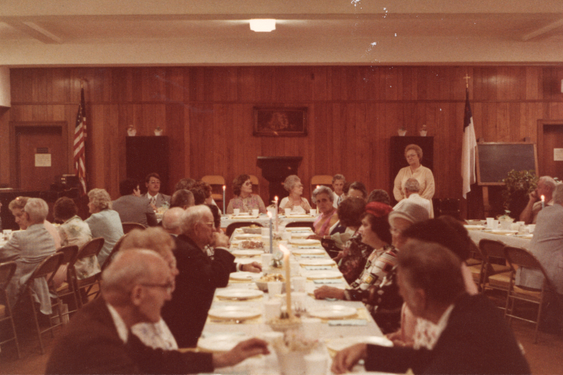 Congregants dine together at long, candlelit tables