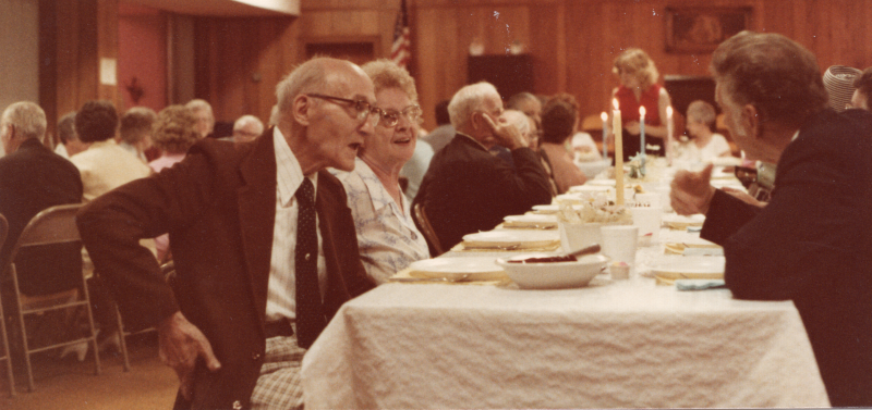 Congregants smile as they speak to each other at a meal fellowship