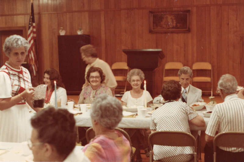 Congregants dine together at long, candlelit tables
