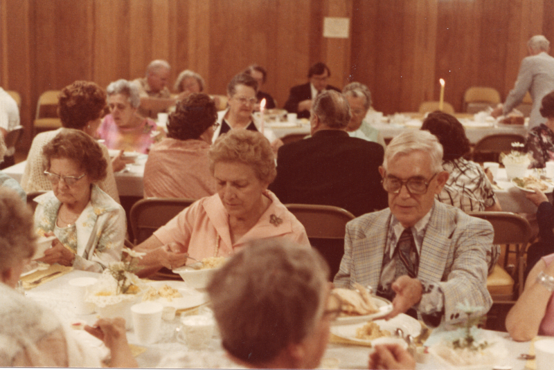 Congregants dine together at long, candlelit tables