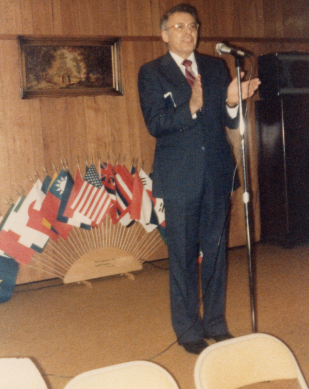 Pastor Bogdan addresses congegrants in front of world flags