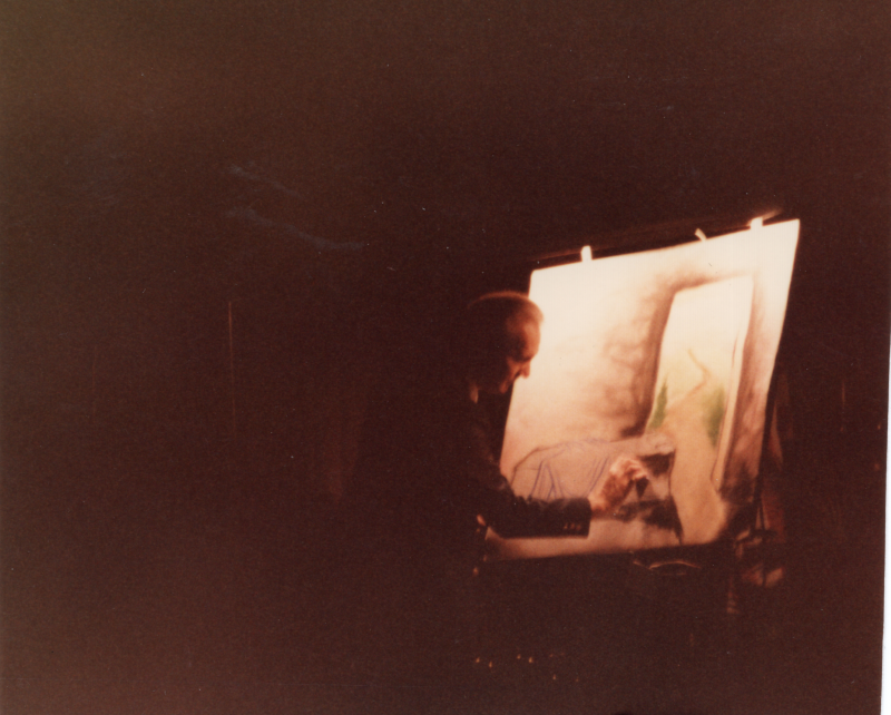 A man draws on an illuminated screen while three peeople sing