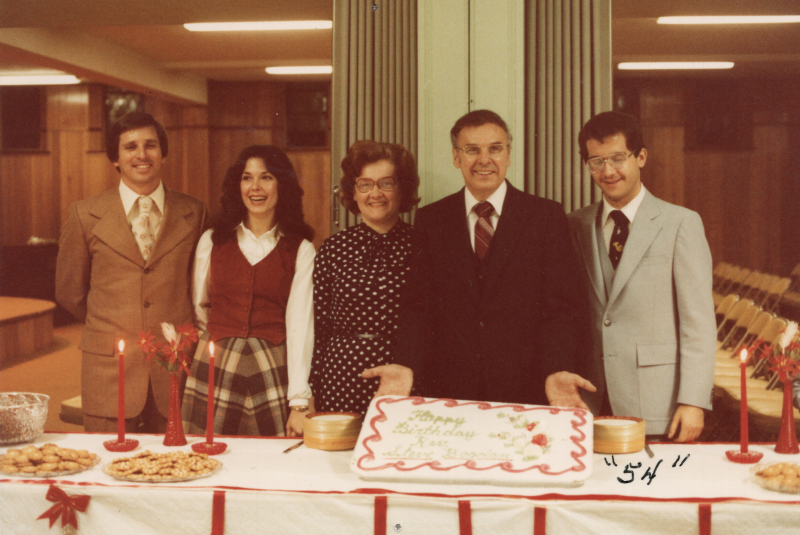 Pastor Bogdan and his family pose with his birthday cake. The number "54" has been added to the photograph with a pen
