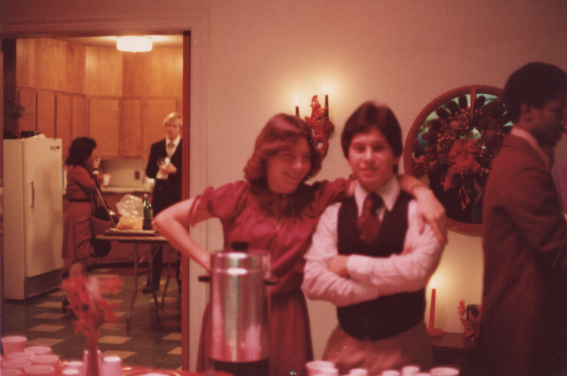 A man and a woman pose for a portrait with other congregants walking behind them