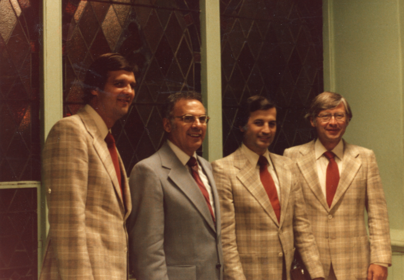 Pastor Roberson smiles for a photograph with three men in matching suits