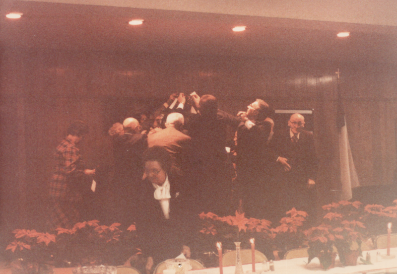 Men decorate a Christmas tree with pointsettias in front of dining tables