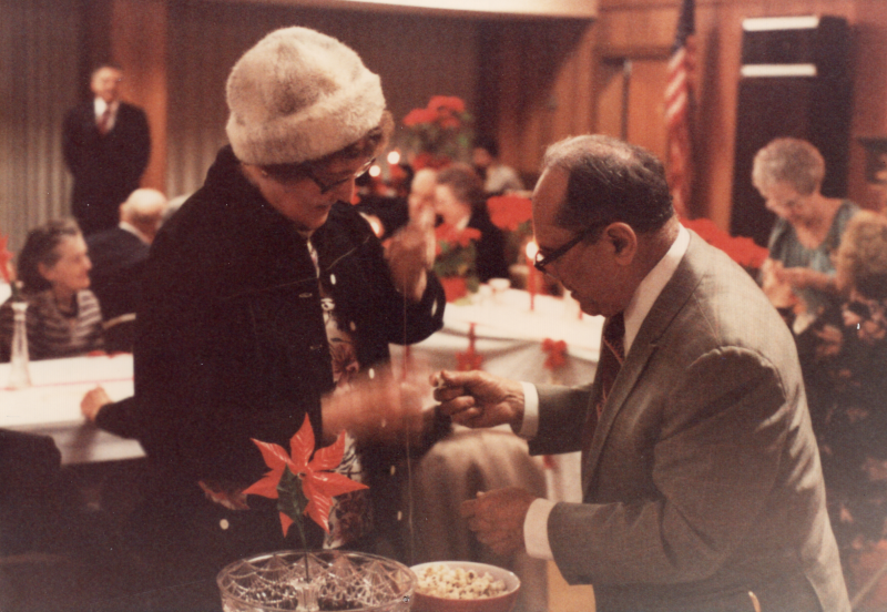 A man and wooman exchange something surrounded by Christmas decorations