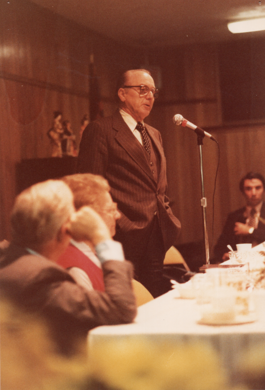 A man speaks into a microphone at a fellowship meal