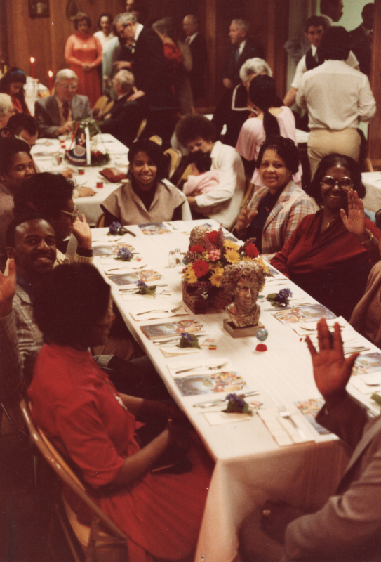 A group waves to the camera before they dine together
