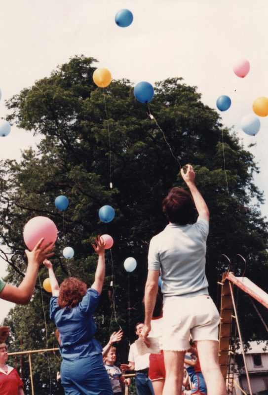 A group of women release blue, pink, and yellow balloons