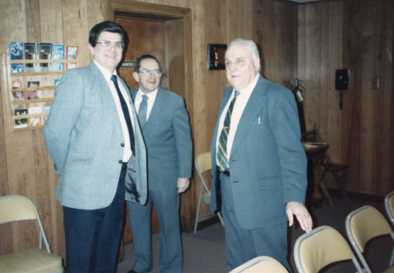Three men, including John Bugeida, speak with each other