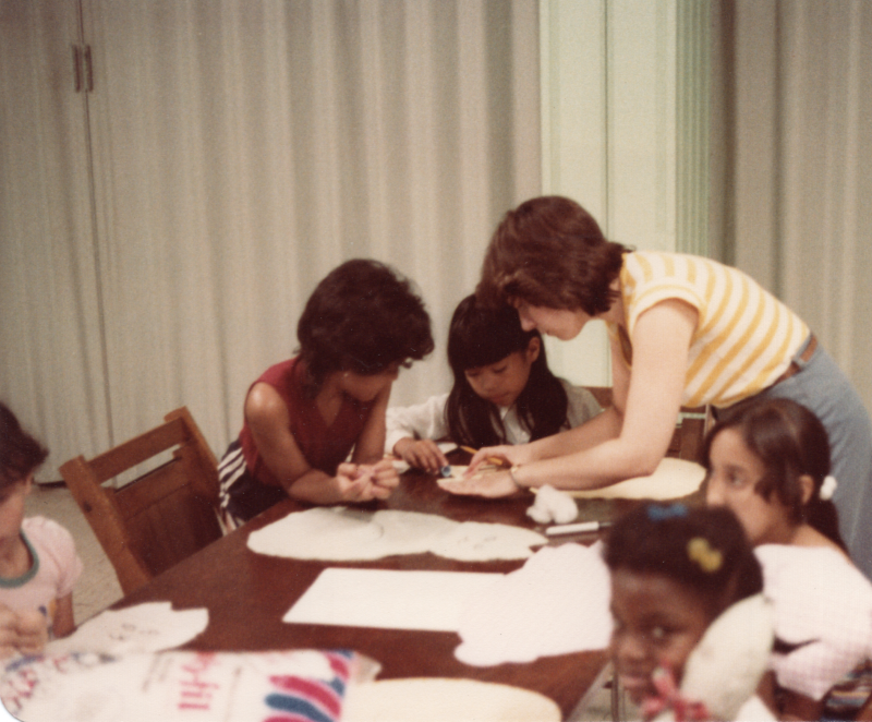 Children work on crafts with an adult volunteer