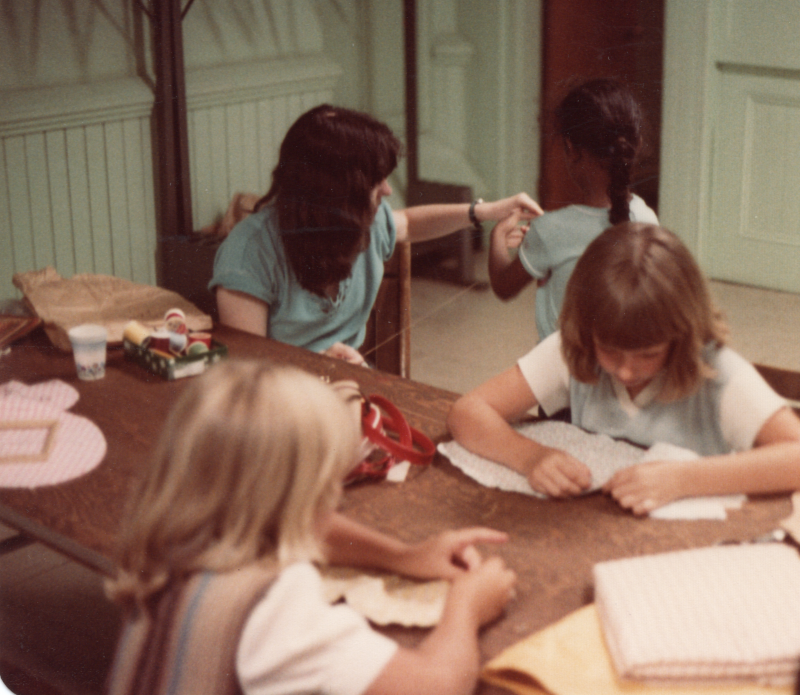 Children work on crafts with an adult volunteer
