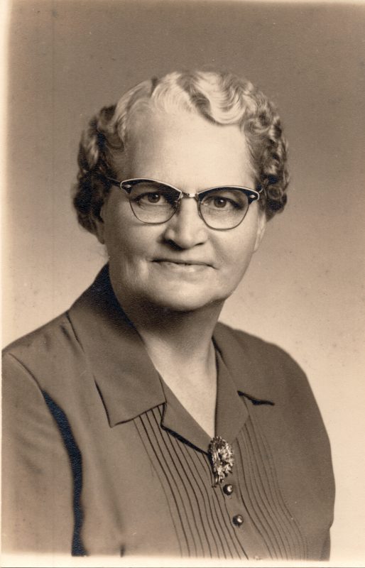 An older woman with glasses smiles for a portrait