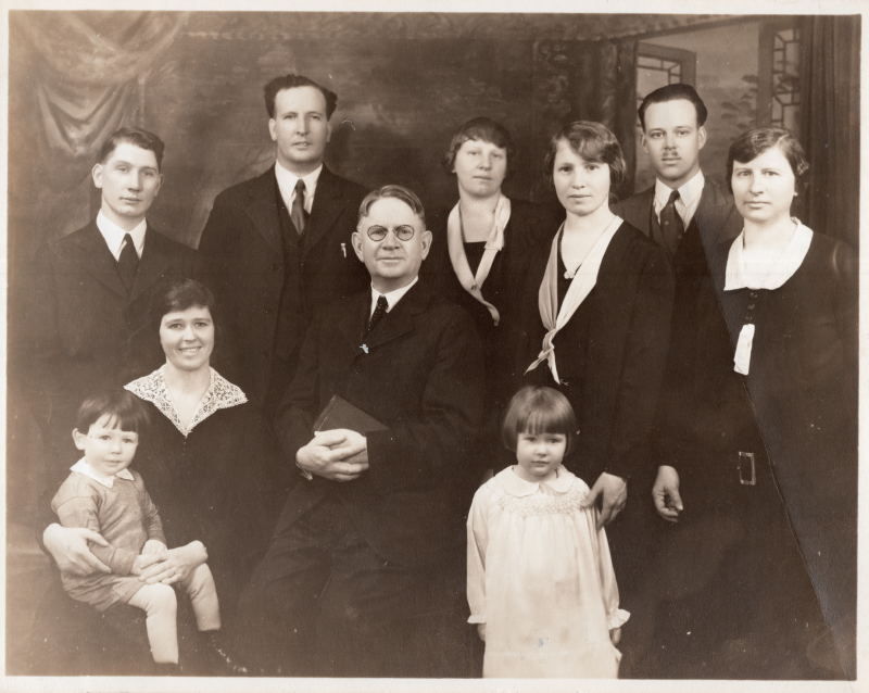 Rev. Flem Van Meter smiles for a portrait holding a Bible surrounded by his family